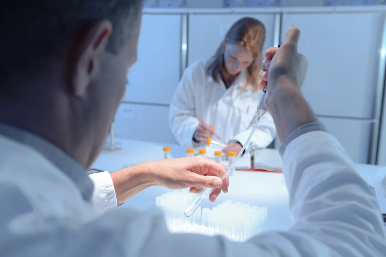Man holding pipette in laboratory.